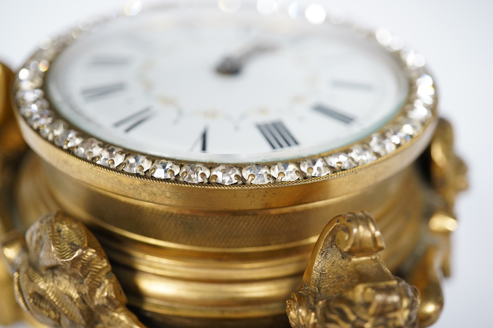 A 19th century French ormolu table timepiece decorated with paste jewelling edged dial and three classical figures, widest point 15cm. Condition - good, not been checked as working